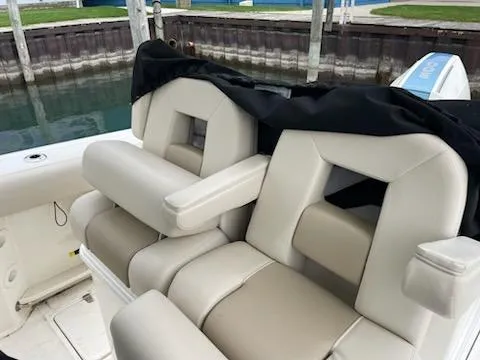 Slide: The Image of 2022 Boston Whaler 280 Outrage boat seats, beige upholstery, docked by water. - 12