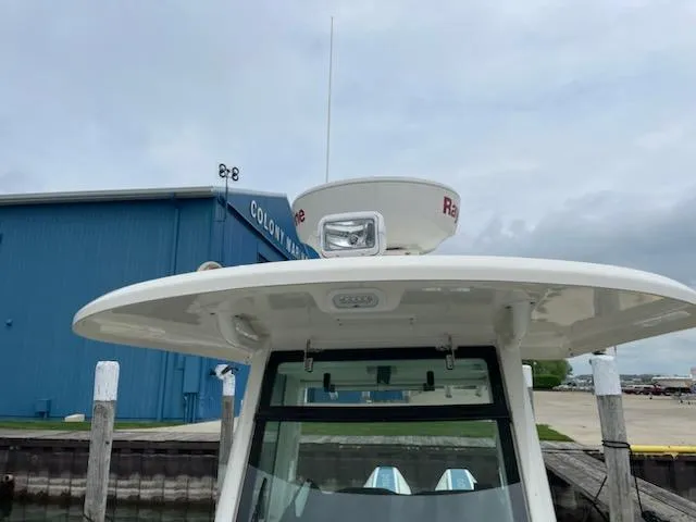 Slide: The Image of 2022 Boston Whaler 280 Outrage boat with radar, docked near a blue building. - 3