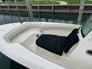 Slide: The Image of 2022 Boston Whaler 280 Outrage boat interior with cushioned seating, docked by the water. - 7