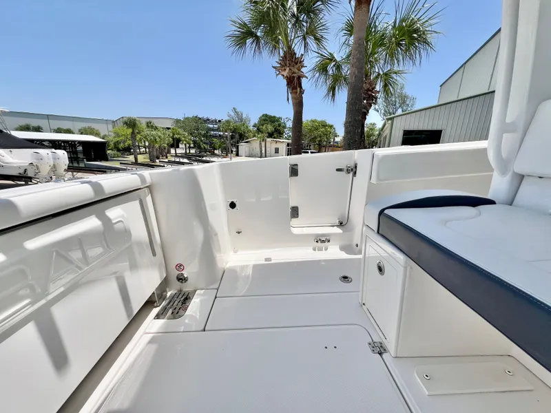 Slide: The Image of 2021 Robalo R360 Center Console boat interior with seating, palm trees, and clear sky. - 11