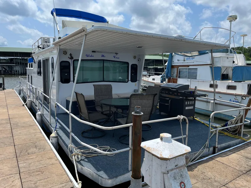 Slide: The Image of 1987 Sumerset Custom houseboat docked with outdoor seating and grill under a canopy. - 2