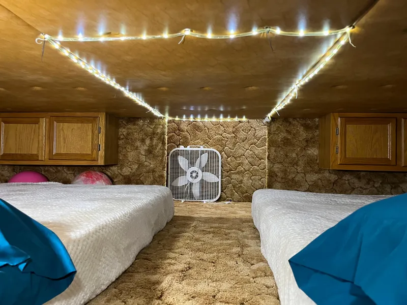 Slide: The Image of Cozy 1987 Sumerset Custom interior with twin beds, string lights, and a fan. - 24