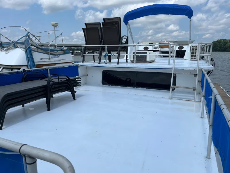 Slide: The Image of 1987 Sumerset Custom houseboat with spacious deck, blue canopy, and outdoor seating. - 5