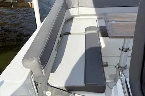 Slide: The Image of 2020 Jeanneau Leader 9.0 CC boat seating area with gray cushions and wooden table. - 19