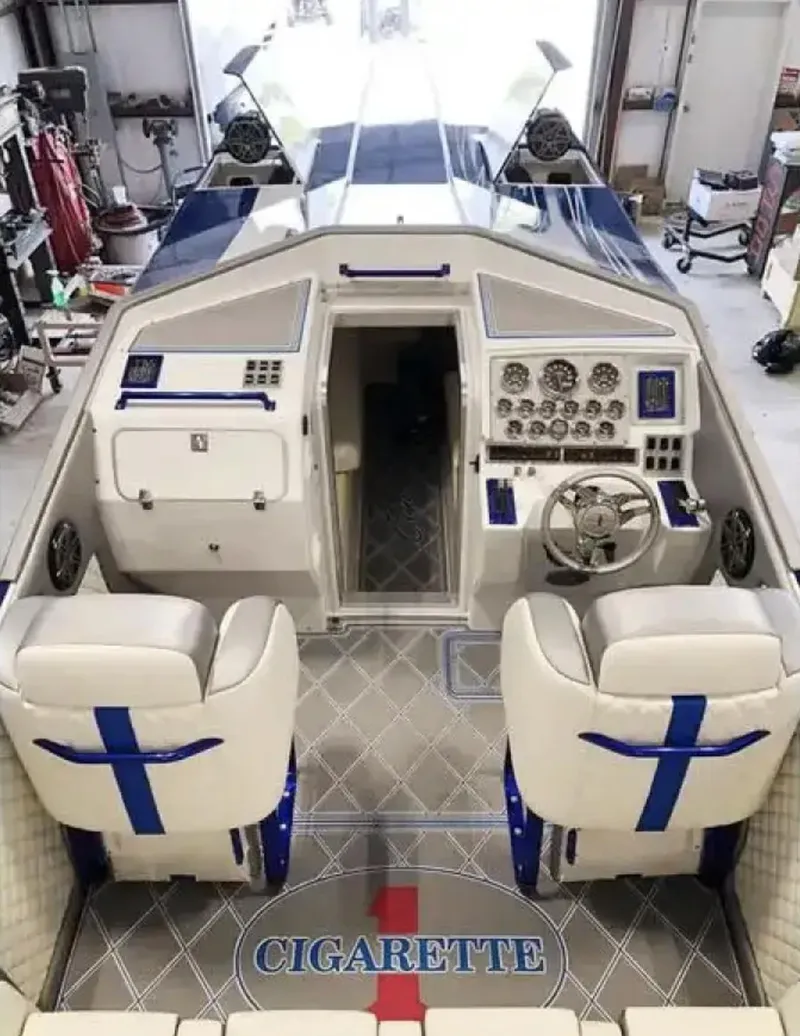 Slide: The Image of 1989 Cigarette 35 Cafe Racer boat interior with white and blue seating, dashboard, and controls. - 10