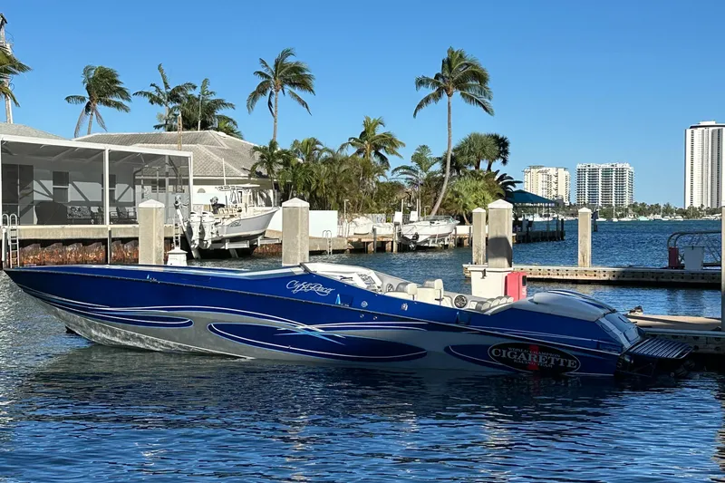 Slide: The Image of 1989 Cigarette 35 Cafe Racer boat docked in a sunny marina with palm trees. - 2