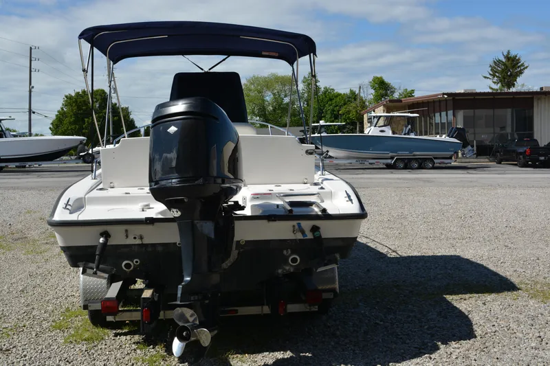 Slide: The Image of 2006 Boston Whaler 220 Dauntless boat with outboard motor, parked on gravel lot. - 2