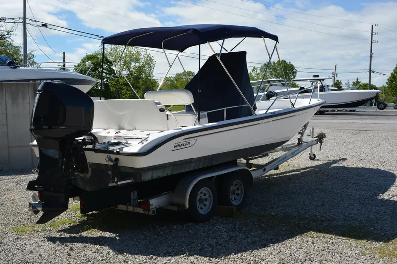 Slide: The Image of 2006 Boston Whaler 220 Dauntless boat on trailer with canopy, parked outdoors. - 3