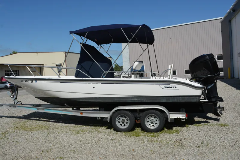 Slide: The Image of 2006 Boston Whaler 220 Dauntless boat on trailer with canopy, parked outdoors. - 5
