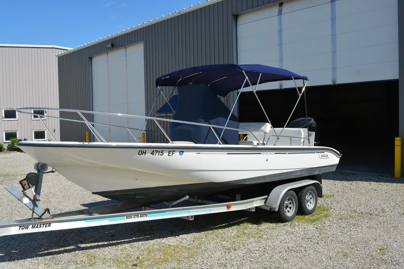 Slide: The Image of 2006 Boston Whaler 220 Dauntless boat on trailer, parked outside a large garage. - 6