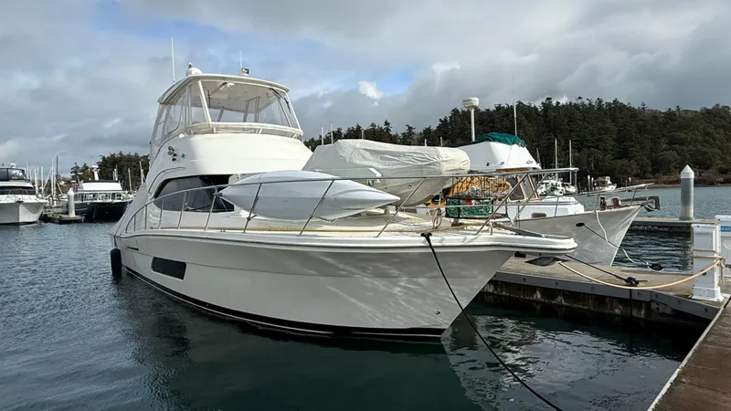 The Image of 2011 Riviera 43 IPS Open Flybridge yacht docked at marina under cloudy sky. - 0