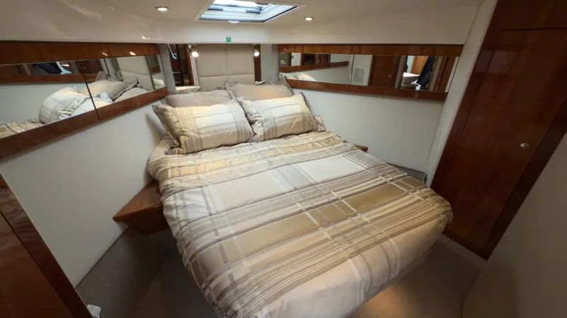 Slide: The Image of Luxurious bedroom in 2011 Riviera 43 IPS Open Flybridge yacht, featuring elegant bedding and wood accents. - 11