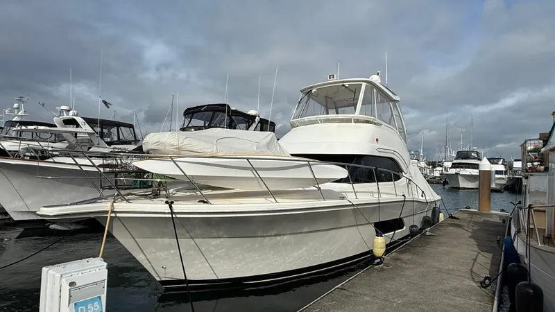 Slide: The Image of 2011 Riviera 43 IPS Open Flybridge yacht docked at marina under cloudy sky. - 1
