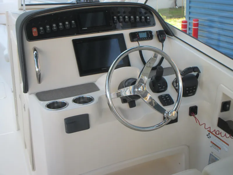 Slide: The Image of 2018 Grady-White Freedom 307 boat dashboard with steering wheel and control panel. - 23
