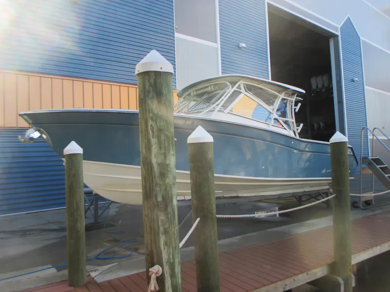 Slide: The Image of 2018 Grady-White Freedom 307 boat docked near a blue building. - 3