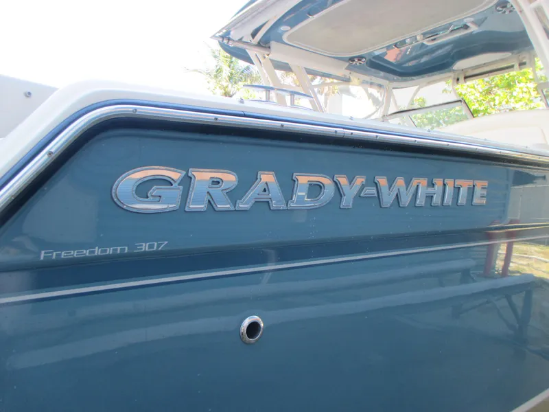 Slide: The Image of 2018 Grady-White Freedom 307 boat, blue exterior with logo and model name. - 8