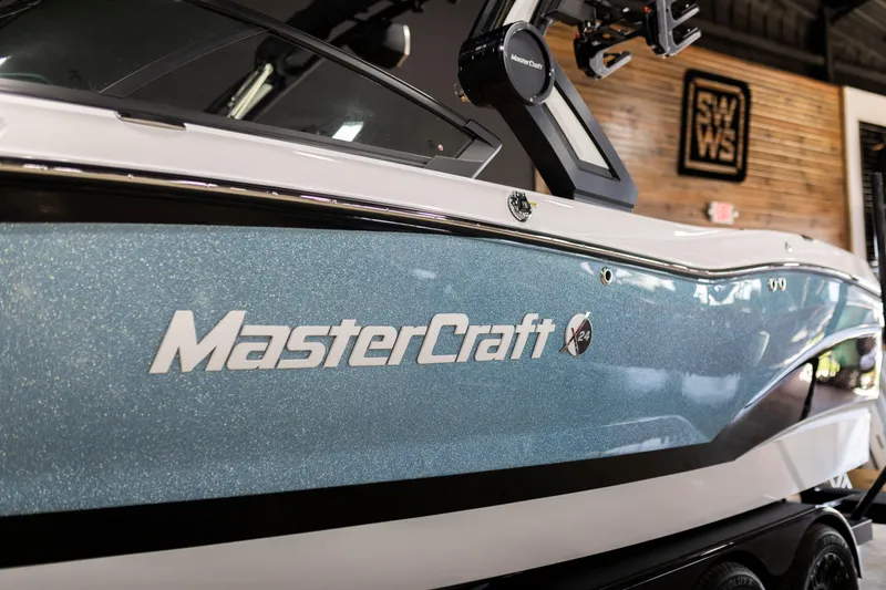 Slide: The Image of 2024 MasterCraft X24 boat with sleek blue design in showroom. - 4