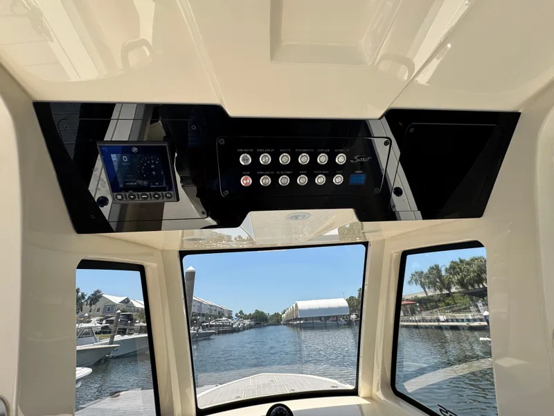 Slide: The Image of Interior view of 2025 Scout 281 XSS boat dashboard with control panel and waterway scenery. - 13