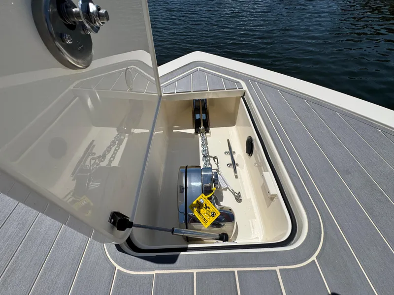 Slide: The Image of 2025 Scout 281 XSS boat anchor compartment with open hatch, showing chain and winch. - 22