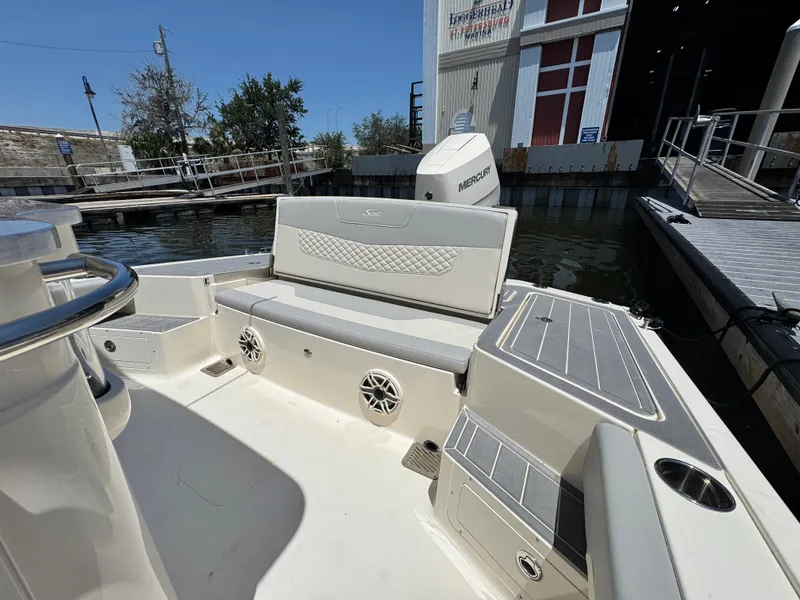 Slide: The Image of 2025 Scout 281 XSS boat interior with seating and storage, docked by a marina. - 7