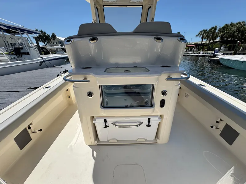 Slide: The Image of 2025 Scout 281 XSS boat interior with seating and storage, docked by the water. - 8