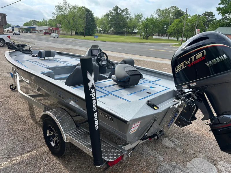Slide: The Image of 2025 Xpress H18 boat with Yamaha motor on a trailer, parked outdoors. - 2