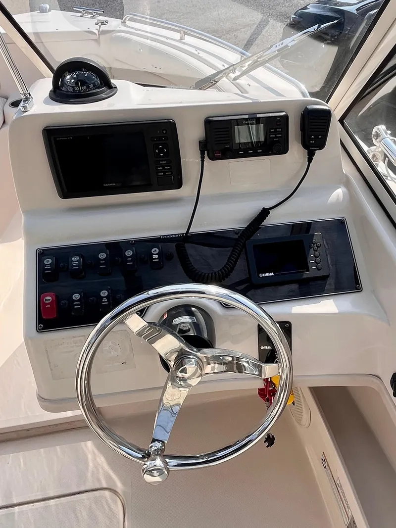 Slide: The Image of 2017 Grady-White Freedom 192 boat dashboard with steering wheel and navigation controls. - 9