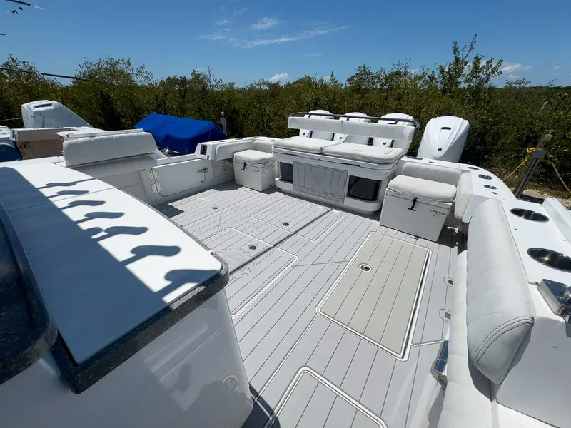 Slide: The Image of 2019 HCB 53 Sueños boat deck with seating, storage, and engines, under clear blue sky. - 12