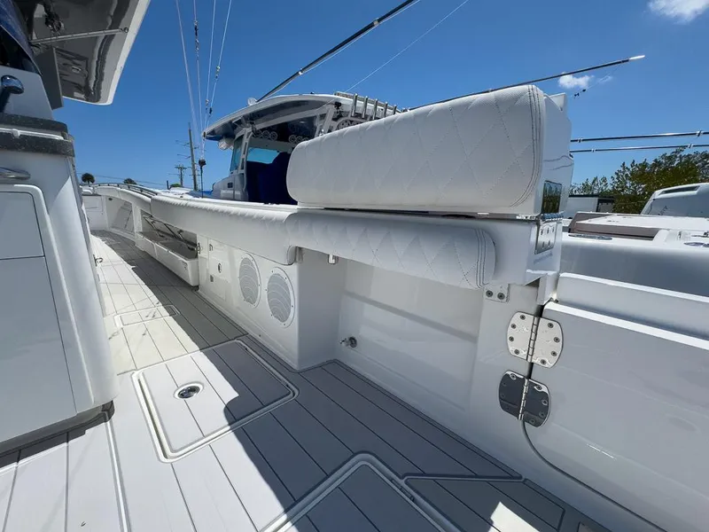 Slide: The Image of 2019 HCB 53 Sueños boat deck with white seating and speakers under a clear blue sky. - 27