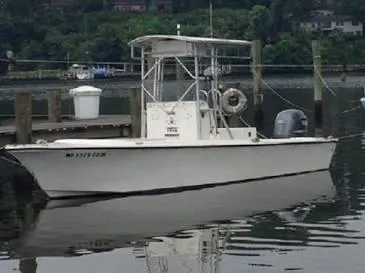 Slide: The Image of A 1999 Custom pump out boat docked by a calm waterfront. - 2
