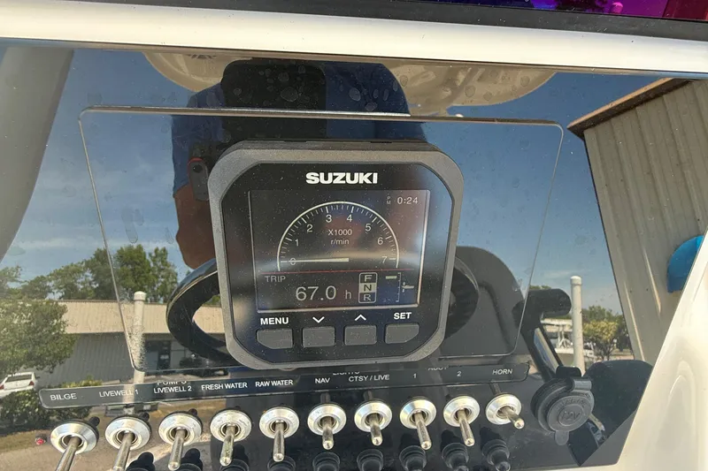 Slide: The Image of 2021 Sea Pro 248 Bay dashboard with Suzuki display and control switches. - 18