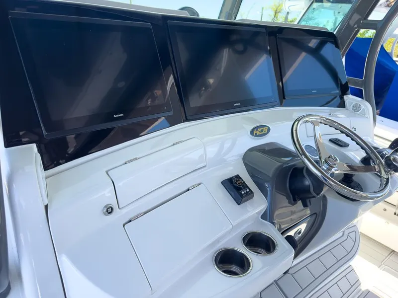 Slide: The Image of 2019 HCB 53 Sueños boat dashboard with three screens and steering wheel. - 16