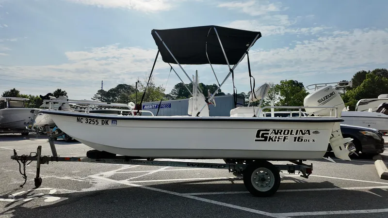 Slide: The Image of 2008 Carolina Skiff 16 DLX boat on trailer, parked outdoors under a clear sky. - 12
