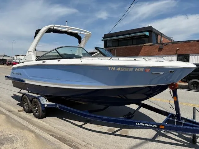 Slide: The Image of 2023 Chaparral 267 SSX boat on trailer, parked on street, under clear sky. - 1