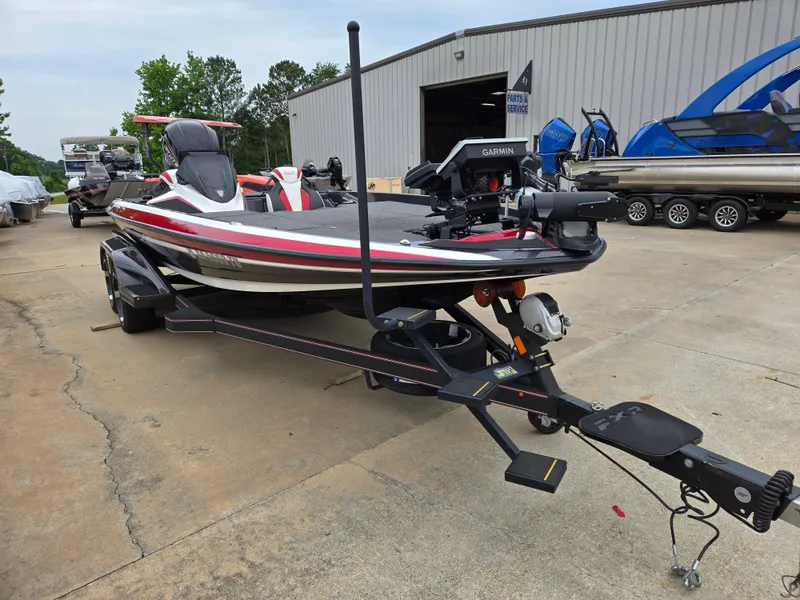 Slide: The Image of 2022 Skeeter FXR 20 Limited boat on trailer, parked outdoors near a warehouse. - 2