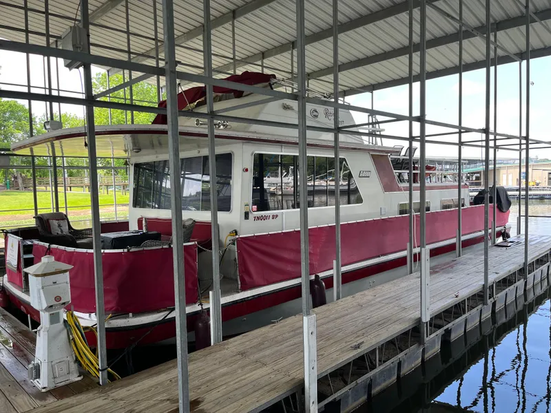Slide: The Image of 1988 Gibson Standard boat docked under covered marina with red accents and wooden walkway. - 0