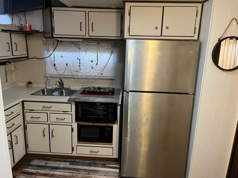 Slide: The Image of Compact kitchen with stainless steel fridge, white cabinets, and a small stove. - 18