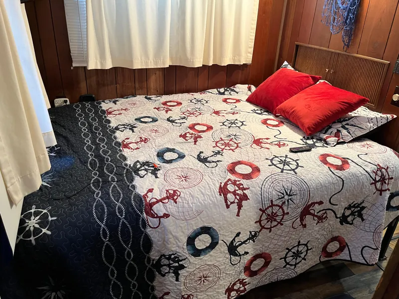 Slide: The Image of Cozy bedroom with nautical-themed bedding, red pillows, and wood-paneled walls. - 23