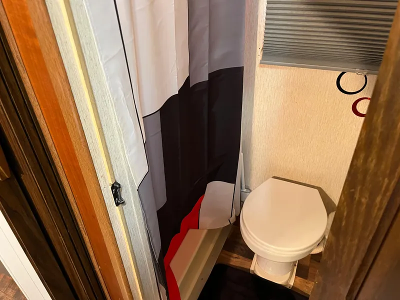 Slide: The Image of Small bathroom with shower curtain, toilet, and wooden accents. - 27