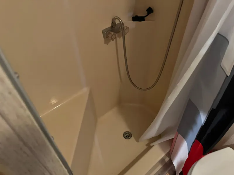 Slide: The Image of A compact shower area with a curtain and handheld showerhead. - 30