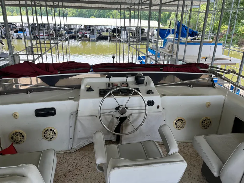 Slide: The Image of 1988 Gibson Standard boat helm with steering wheel, seats, and marina view. - 6