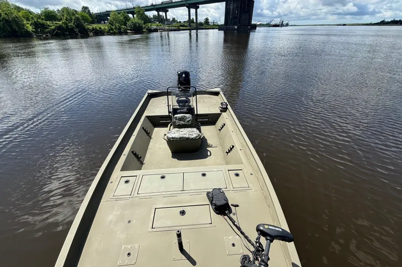 Slide: The Image of 2024 Tracker Grizzly 2072 SC boat on a calm river with a bridge in the background. - 6
