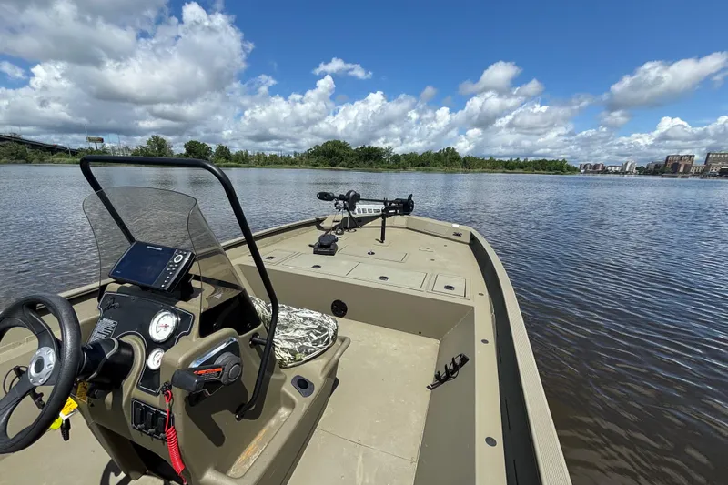 Slide: The Image of 2024 Tracker Grizzly 2072 SC boat on a calm lake under a blue sky. - 8