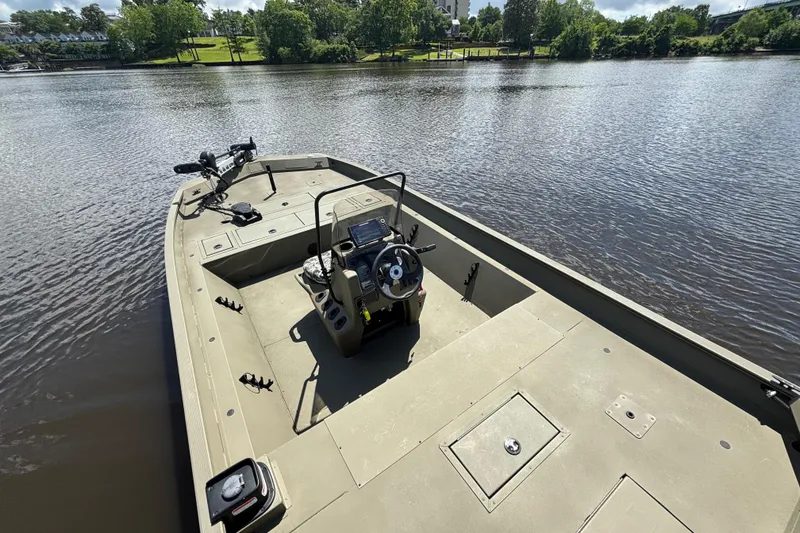 Slide: The Image of 2024 Tracker Grizzly 2072 SC boat on a calm lake, showcasing spacious deck and steering console. - 9