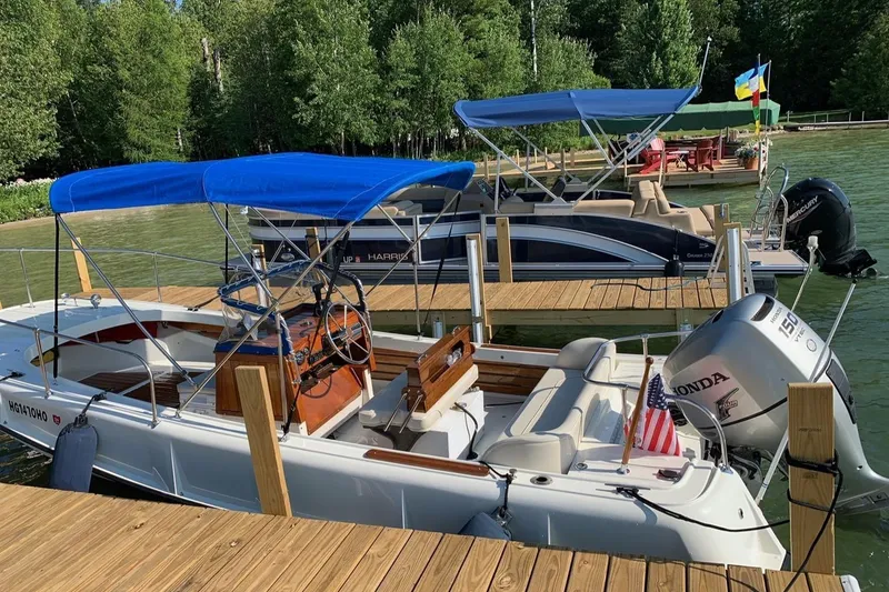 Slide: The Image of 1972 Boston Whaler Outrage Rib Side docked with blue canopy, surrounded by lush greenery. - 2