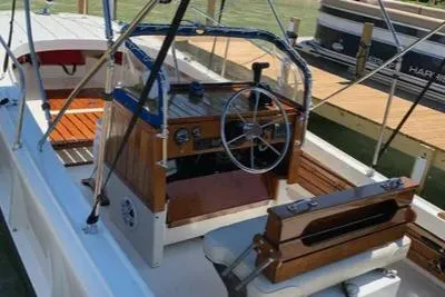 Slide: The Image of 1972 Boston Whaler Outrage Rib Side boat with wooden console and seating, docked by the water. - 3