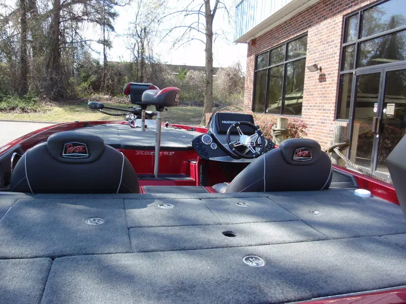 Slide: The Image of 2017 Ranger Z518 Comanche boat with seating and steering wheel, parked near a brick building. - 6