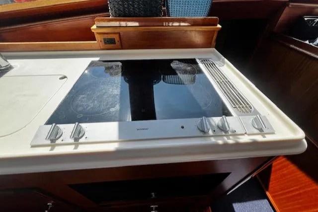 Slide: The Image of 2003 Lyman-Morse Wesmac Sportfish Cruiser kitchen with modern stovetop and wooden cabinetry. - 13