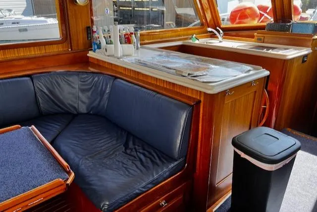 Slide: The Image of 2003 Lyman-Morse Wesmac Sportfish Cruiser interior with blue seating and wooden cabinetry. - 16