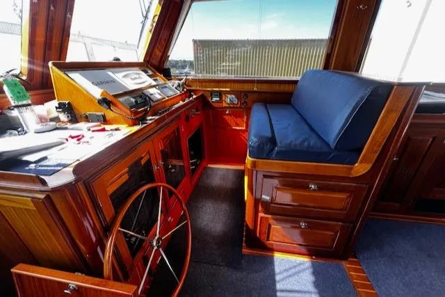 Slide: The Image of 2003 Lyman-Morse Wesmac Sportfish Cruiser interior with wooden helm and blue cushioned seating. - 2